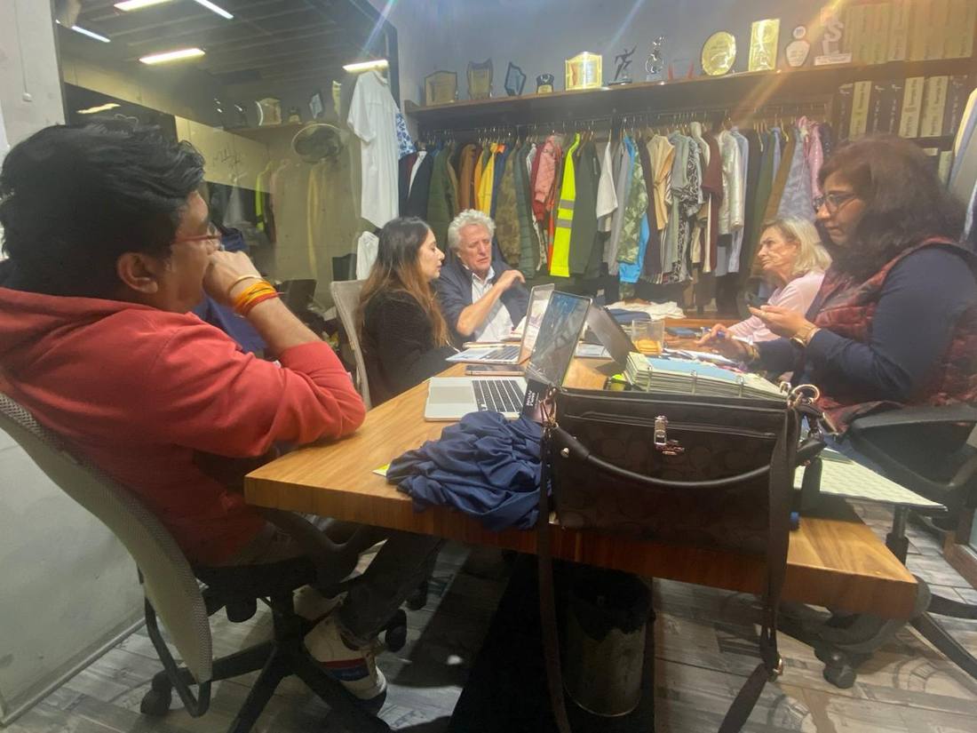 Buyers and the Alliance design team reviewing samples and tech packs at the studio table in Faridabad