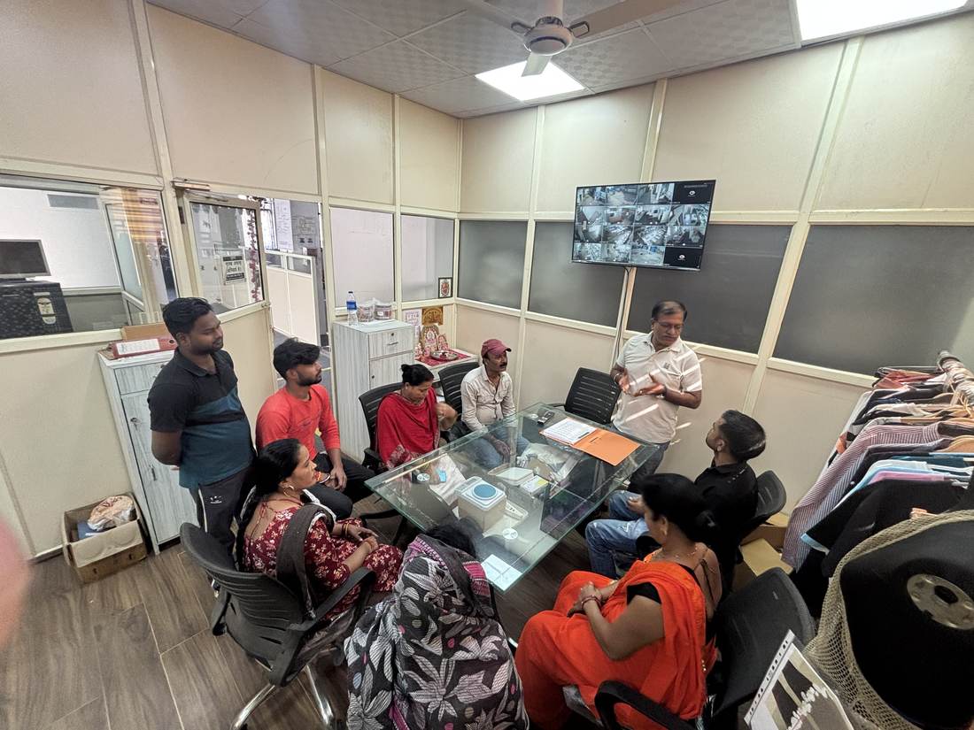 Alliance Company team gathered for a training and briefing session led by a manager, with the CCTV monitoring wall behind